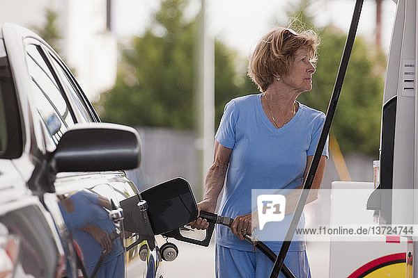 Frau tankt Auto an einer Tankstelle