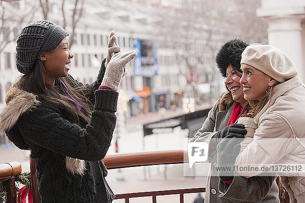 Brazilian woman taking picture of her mother and grandmother with a mobile phone  Boston  Massachusetts  USA