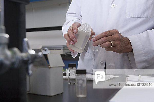 Wissenschaftler gießt Flüssigkeit aus einem Behälter in ein kleines Fläschchen im Labor einer Wasseraufbereitungsanlage