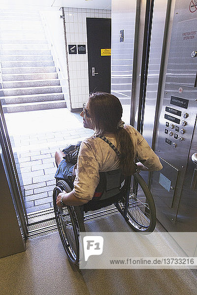 Woman with spinal cord injury in a wheelchair using elevator to train access  Boston  Massachusetts  USA