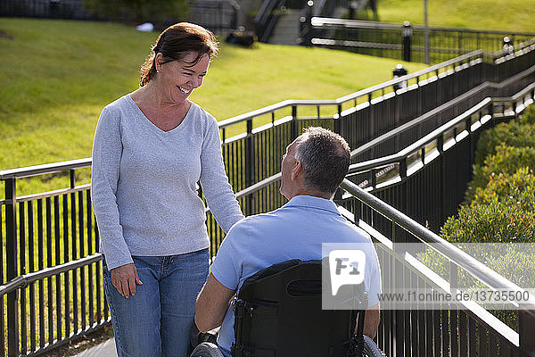 Frau trifft Ehemann im Rollstuhl mit Rückenmarksverletzung auf zugänglicher Rampe