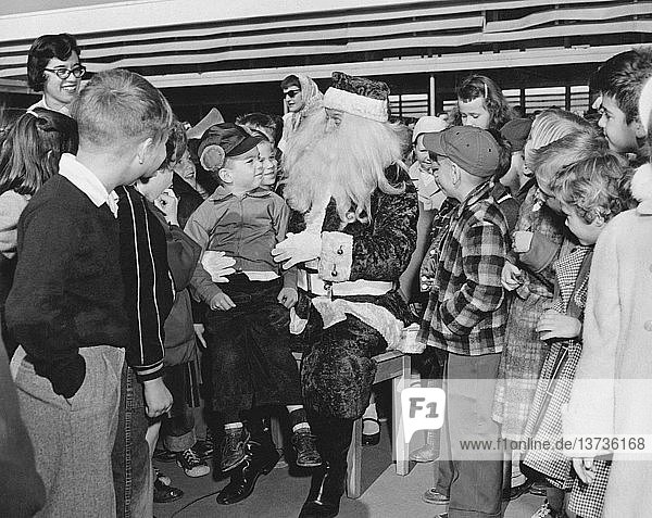 Daly City  Kalifornien: ca. 1955 Eine Schar von Grundschulkindern schart sich um den Weihnachtsmann.