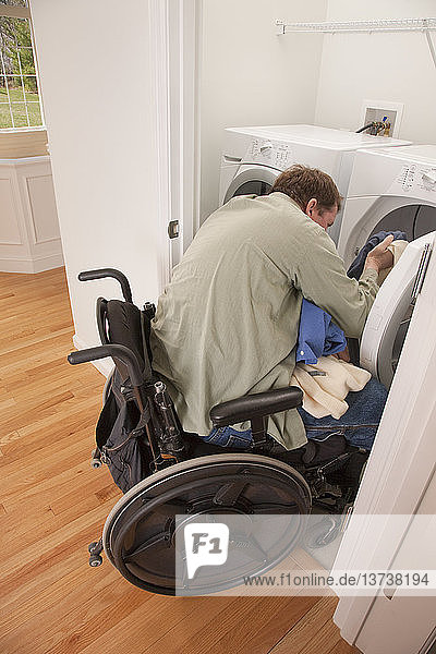 Mann mit Rückenmarksverletzung im Rollstuhl wäscht seine Wäsche zu Hause