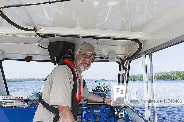 Ingenieur der öffentlichen Arbeiten steuert ein Boot zur Entnahme von Wasserproben auf einem öffentlichen Stausee