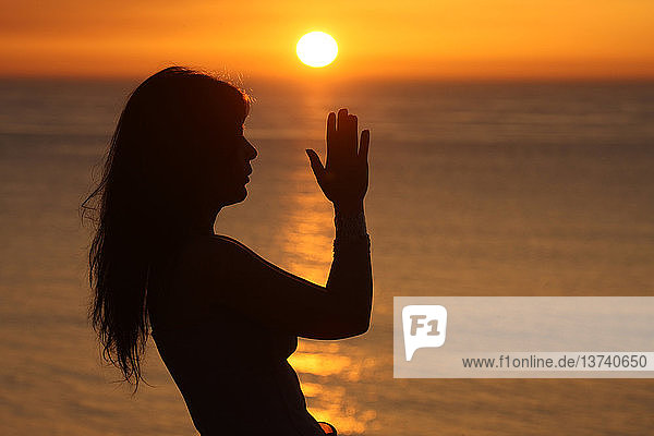 Frau betet bei Sonnenuntergang.