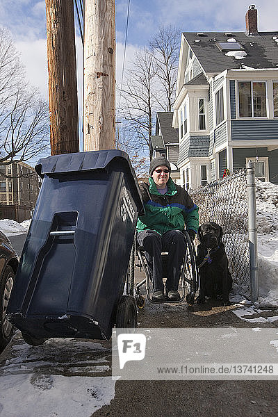 Frau mit Multipler Sklerose macht Recycling mit einem Diensthund im Winter