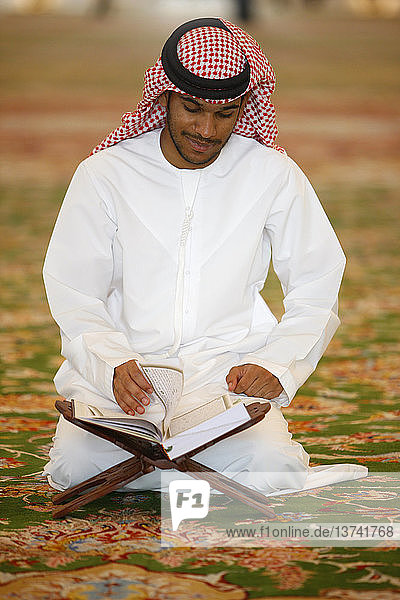 Sheikh Zayed Grand Mosque. Muslim man reading the koran.