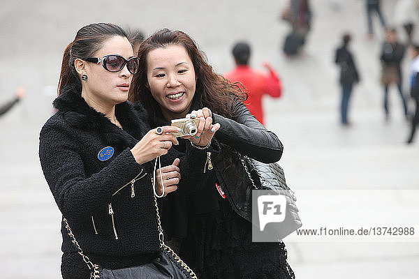 Chinesische Frauen  die sich Bilder auf dem Bildschirm einer Digitalkamera ansehen