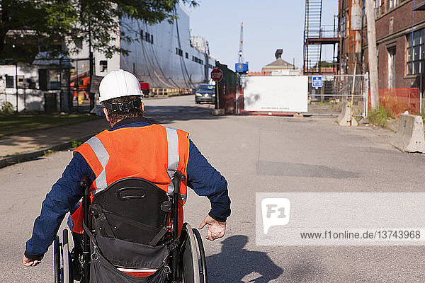 Transportingenieur im Rollstuhl auf dem Trockendock einer Marinewerft