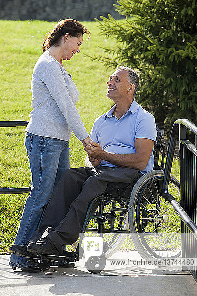 Frau hält Händchen mit Mann im Rollstuhl mit Rückenmarksverletzung auf zugänglicher Rampe