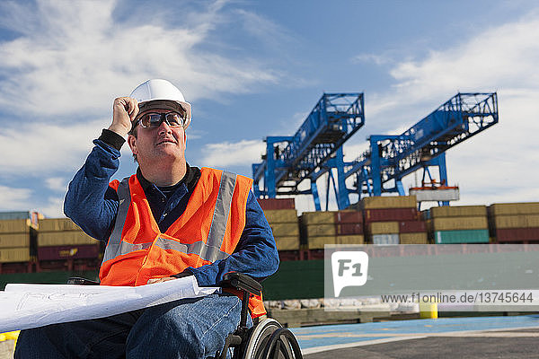 Verkehrsingenieur im Rollstuhl studiert Pläne im Schifffahrtshafen