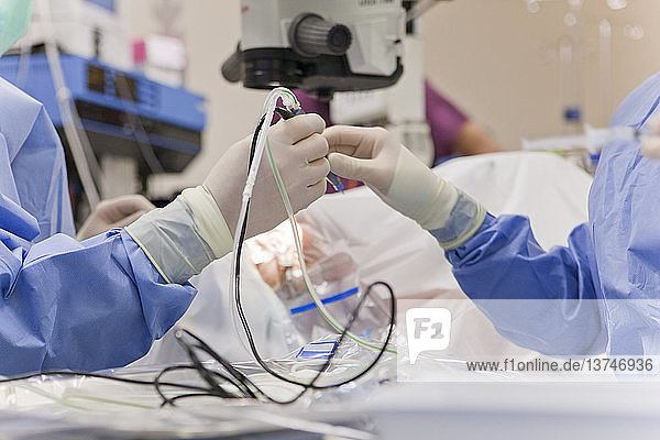 Arzt übergibt Phako-Handstück an Techniker während Kataraktoperation