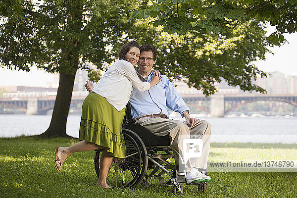 Pregnant woman hugging her husband in a wheelchair with a spinal cord injury