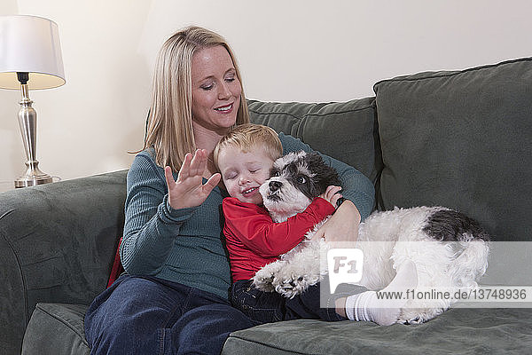 Frau gebärdet das Wort ´Puppy´ in amerikanischer Zeichensprache  während ihr Sohn einen Hund umarmt