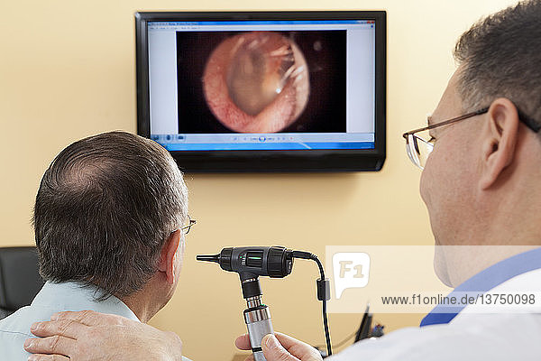 Audiologist doing live video inspection of ear canal while a patient watches on a computer screen