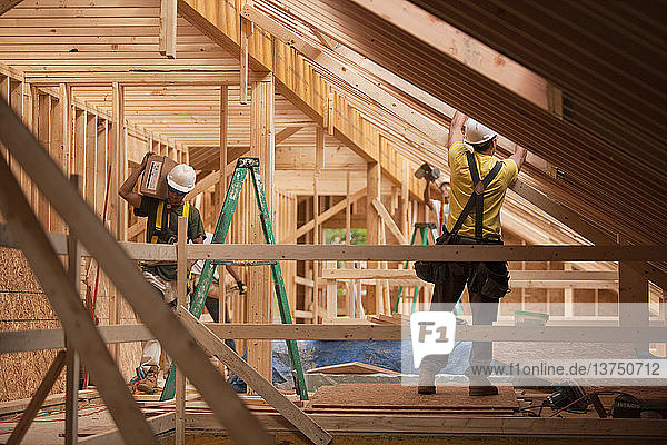 Spanische Zimmerleute bringen die Dachschalung eines im Bau befindlichen Hauses an