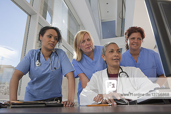 Arzt und Krankenschwestern beraten sich an einem Computer im Krankenhaus