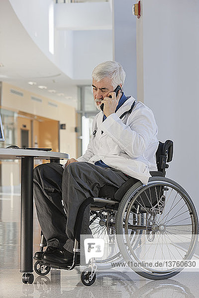 Arzt mit Muskeldystrophie im Rollstuhl spricht mit Smartphone