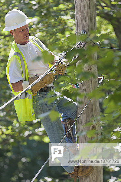 Elektriker auf einem Mast bei Arbeiten an Telefon- und Kabeldrähten