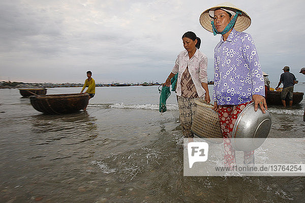 Carrying basket of fish on Mui Ne beach
