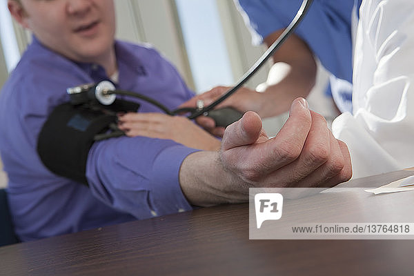 Ärztin und Krankenschwester messen den Blutdruck eines Patienten