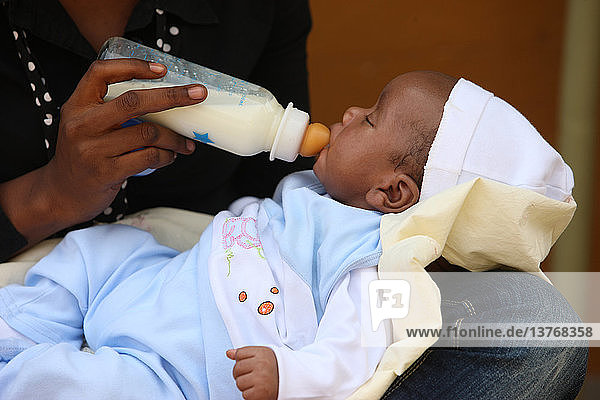 Afrikanische Mutter füttert ihr Baby mit der Flasche