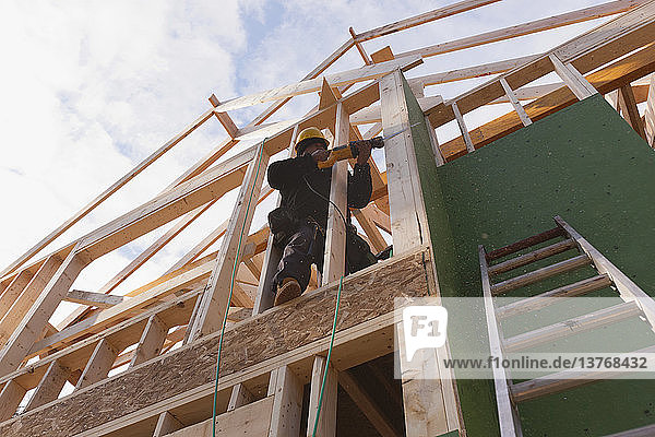 Zimmermann bei der Arbeit mit einer Säbelsäge an einem im Bau befindlichen Haus