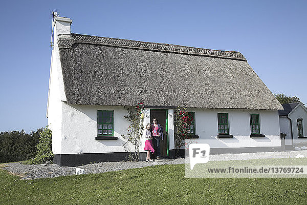 Mutter und Tochter stehen vor der Tür eines reetgedeckten Ferienhauses  Ballyvaughan  Grafschaft Clare  Irland