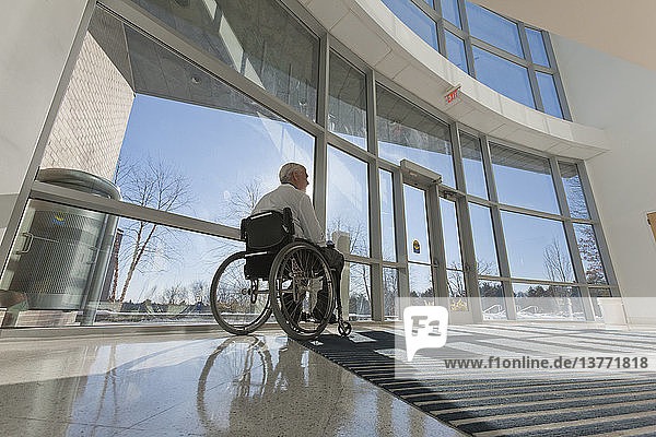 Doctor with muscular dystrophy in wheelchair at hospital entrance