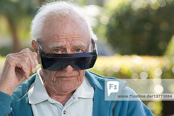 Portrait of a senior man wearing cataract dark glasses