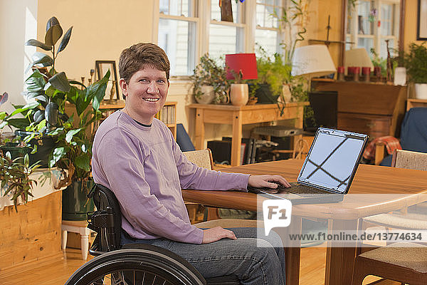 Frau mit Multipler Sklerose benutzt einen Laptop in ihrer barrierefreien Wohnung