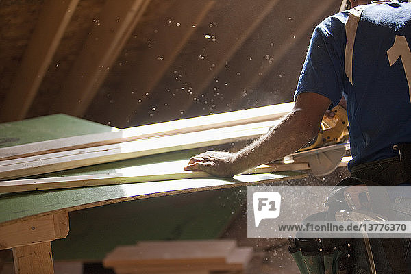 Spanischer Zimmermann bei der Arbeit mit der Kreissäge an einer Zierleiste in einem im Bau befindlichen Haus