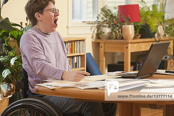 Geschäftsfrau mit Multipler Sklerose im Rollstuhl ist es leid  ihren Papierkram zu erledigen