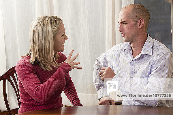 Frau gebärdet das Wort ´Fine´ in amerikanischer Zeichensprache  während sie mit einem Mann kommuniziert