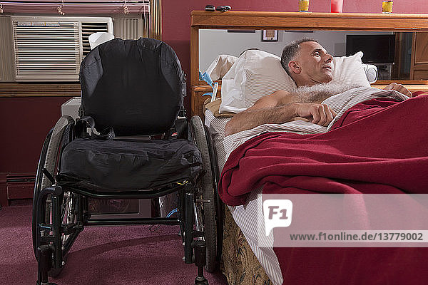 Mann mit Rückenmarksverletzung schläft auf dem Bett