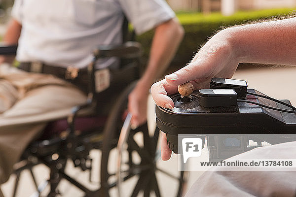 Mann mit Duchenne-Muskeldystrophie steuert einen motorisierten Rollstuhl mit degenerierten Händen