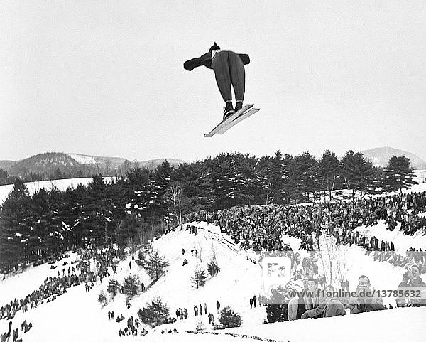 Hanover  New Hampshire: ca. 1955 Rückenansicht eines Skifahrers  der beim jährlichen Winterkarneval des Dartmouth Outing Club von der Schanze springt.