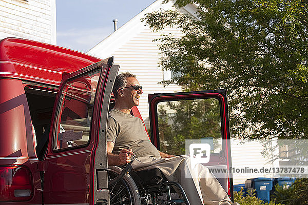 Mann im Rollstuhl wird aus zugänglichem Lieferwagen heruntergelassen