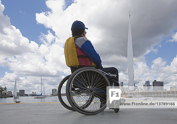 Mann mit Querschnittslähmung im Rollstuhl in einem Hafen