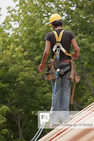 Hispanic carpenter walking on the roof construction of a house