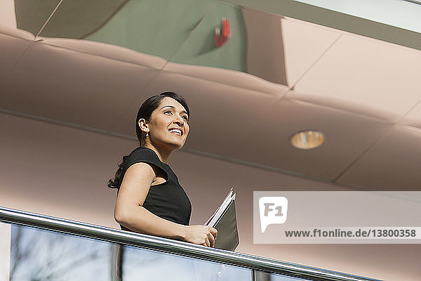 Geschäftsfrau mit Aktenordnern auf der Treppe eines Bürogebäudes