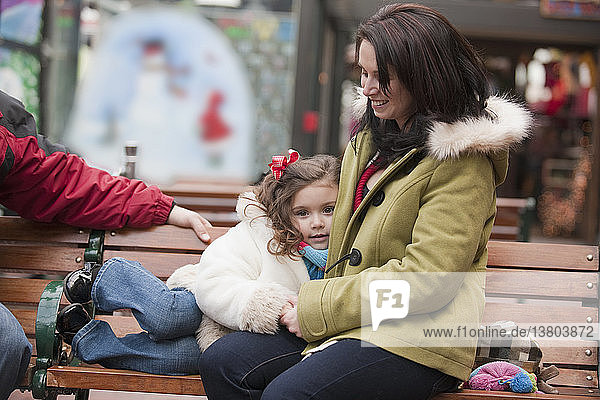 Mädchen sitzt mit seiner Mutter auf einer Bank