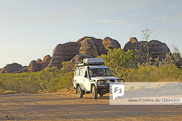 Four-wheel drive vehicle with beehive formations beyond  Purnululu National Park  Kimberley region  Western Australia