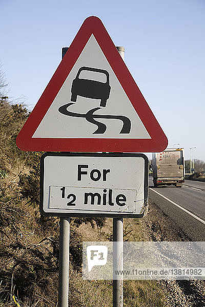 Rotes dreieckiges Straßenschild  das auf einer halben Meile vor glatter Fahrbahn warnt  UK