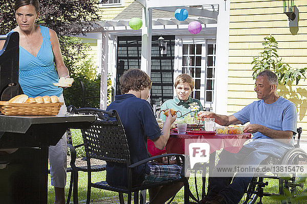 Mann mit Querschnittslähmung im Rollstuhl beim Familienpicknick