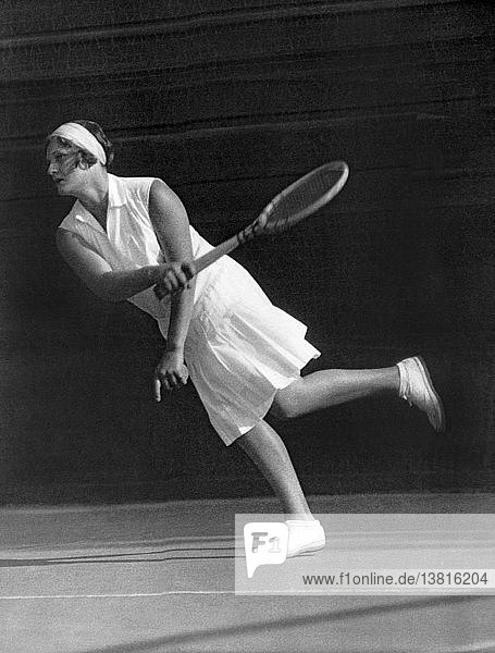 England: ca. 1927 Die britische Tennisspielerin  Olympiasiegerin und Wimbledonsiegerin Kathleen McKane Godfree gibt einen Ball auf dem Tennisplatz zurück.