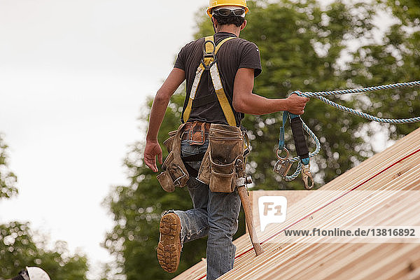 Hispanischer Zimmermann auf dem Dach eines im Bau befindlichen Hauses