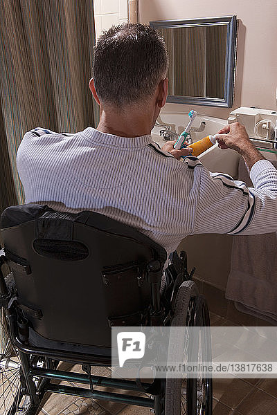 Man with spinal cord injury in a wheelchair brushing his teeth