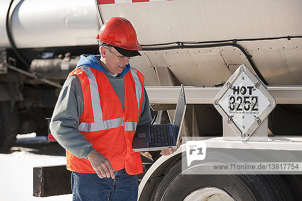 Engineer logging data on a laptop at tanker trucks