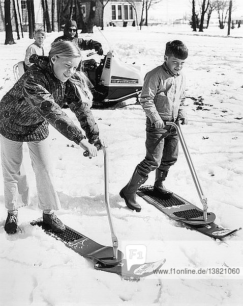 Vereinigte Staaten: ca. 1967 Ein Junge und ein Mädchen schauen etwas unsicher  als sie das neue  lenkbare Skibrett namens Fun-Ski ausprobieren.